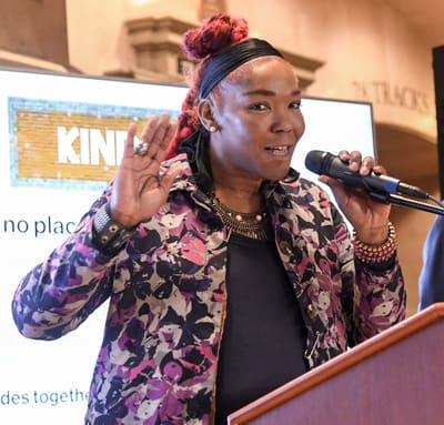 Kiara St. James at a podium speaking into a microphone